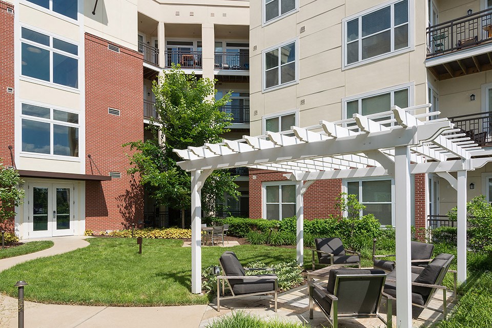 an outdoor courtyard with a white pergola and chairs