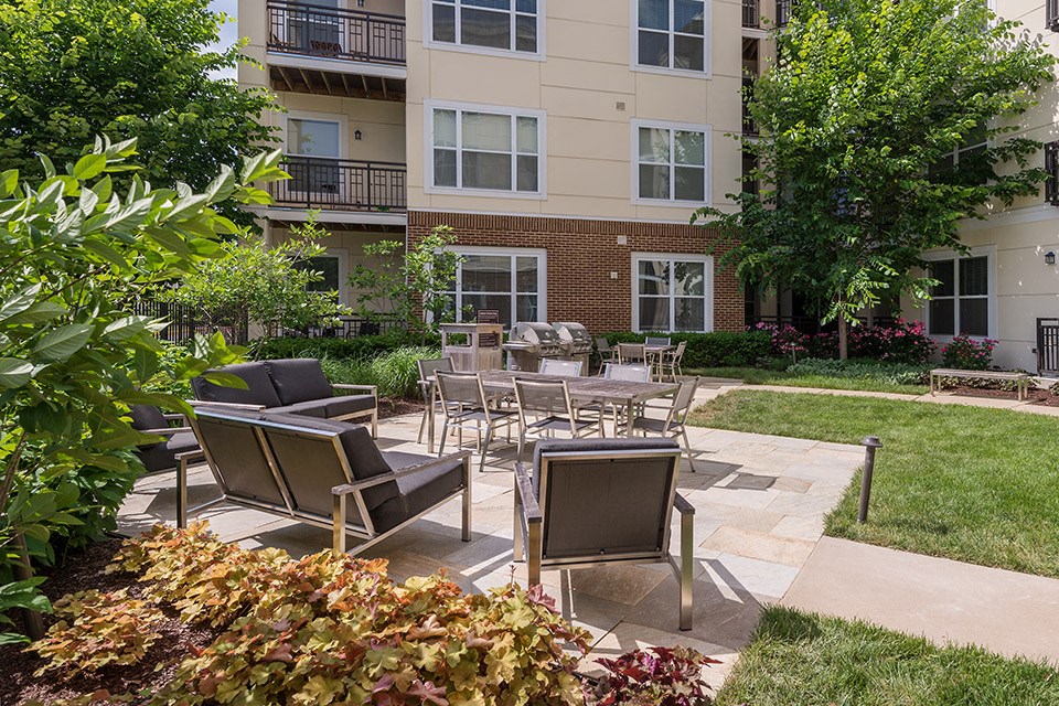 a patio with chairs and tables in front of an apartment building