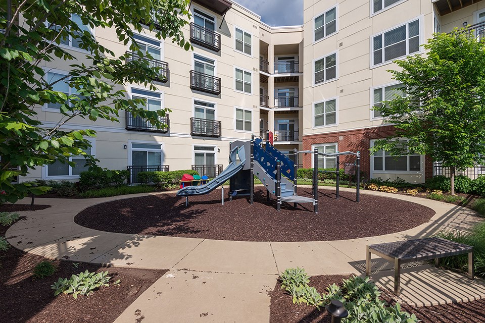 an outdoor playground with a blue slide in front of an apartment building