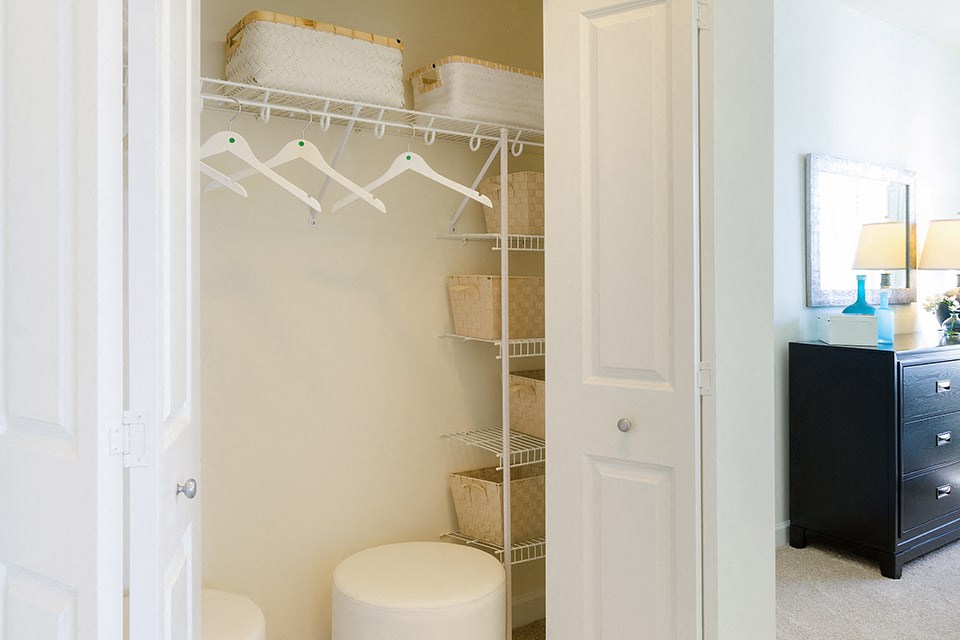a closet with a white toilet and a rack with baskets