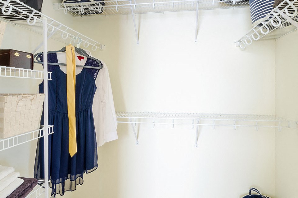 a closet with white shelves and clothes hanging on it