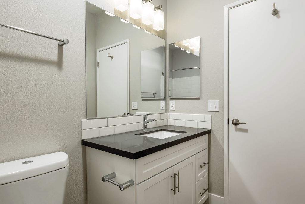 A bathroom with a sink, mirror, and toilet.