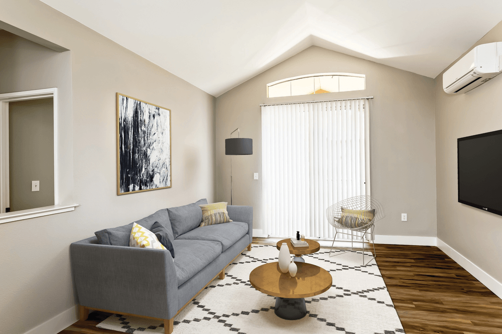 A living room with a grey couch and a painting on the wall.