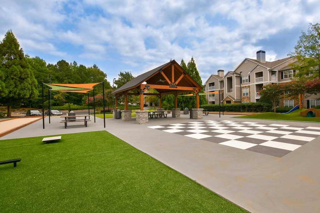 A courtyard with a pavilion and tables and a lawn
