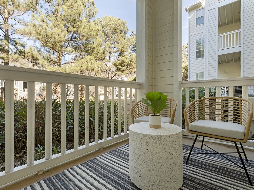 a patio with two chairs and a table on a striped rug