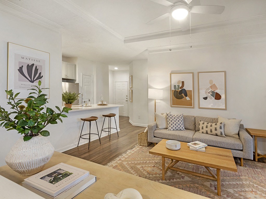 a living area with a couch coffee table and a kitchen in the background