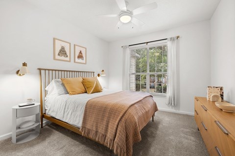 A bedroom with a bed, nightstand, and a ceiling fan.