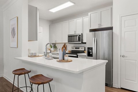 A kitchen with white cabinets and a white countertop.