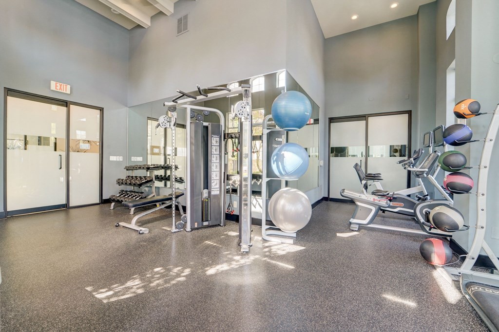 a gym with weights and cardio equipment at the trilogy apartments