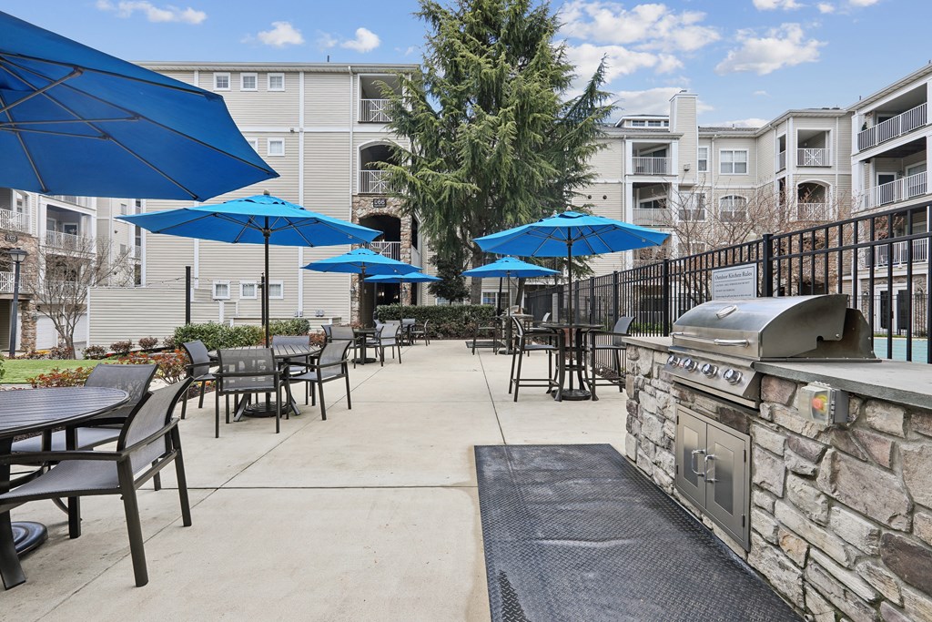 an outdoor patio with umbrellas and tables with chairs and a grill