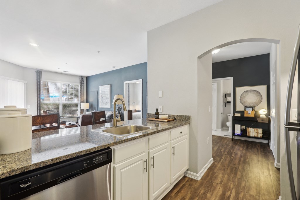 a kitchen with white cabinets and granite counter tops and a sink