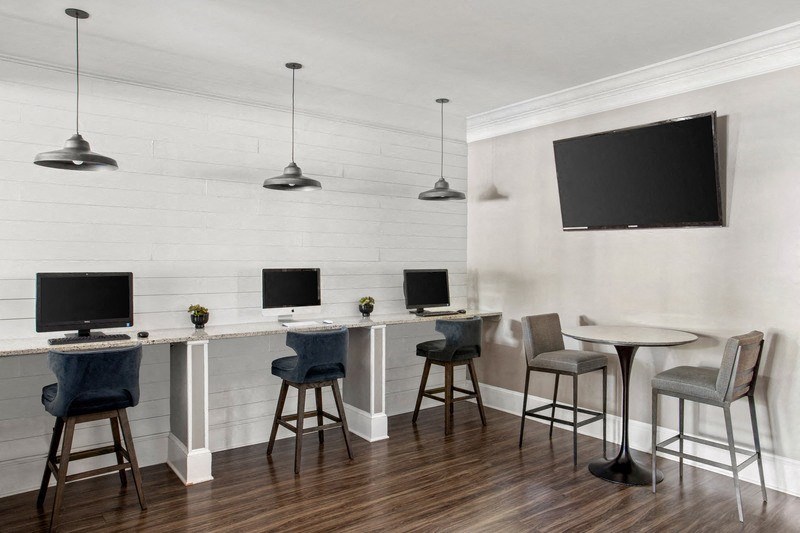 a room with two computer desks and two chairs with a flat screen tv on the wall