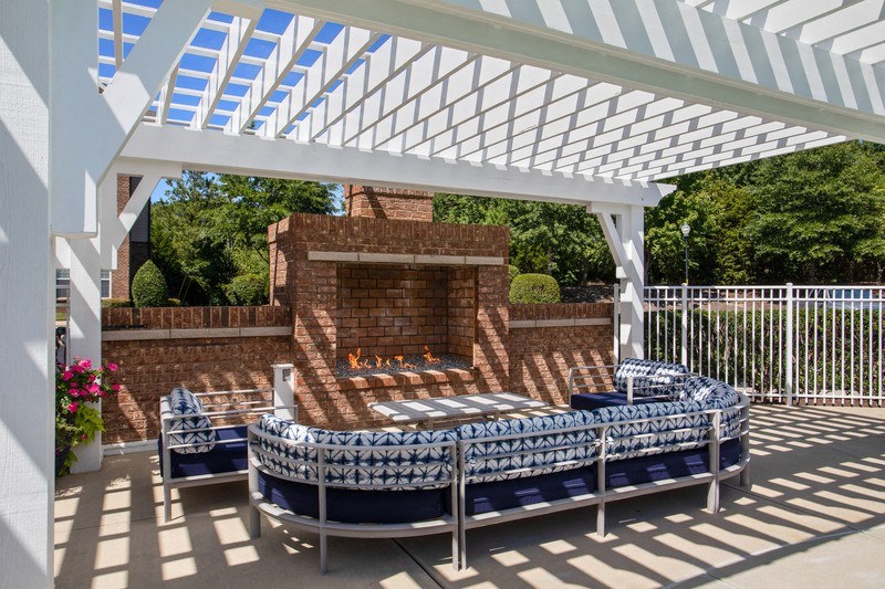 a pergola with a brick fireplace and blue couches