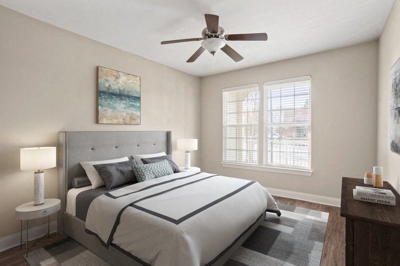 a bedroom with a ceiling fan and two windows