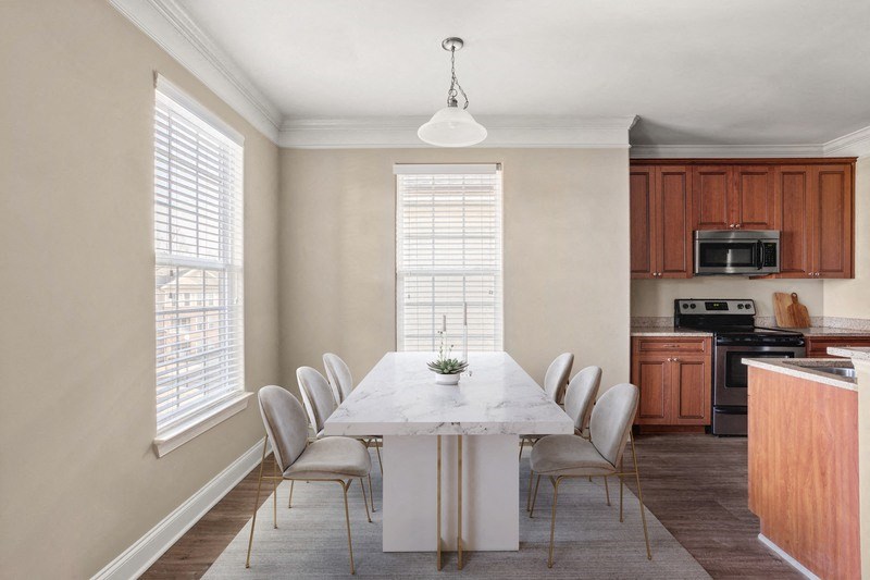 a dining room with a table and chairs and a kitchen in the background