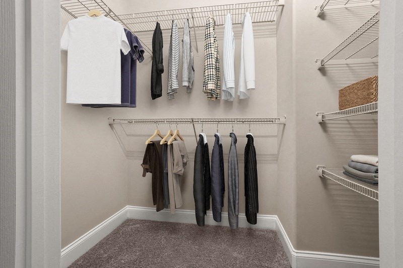a walk in closet with a white shirt and gray pants hanging on the rods