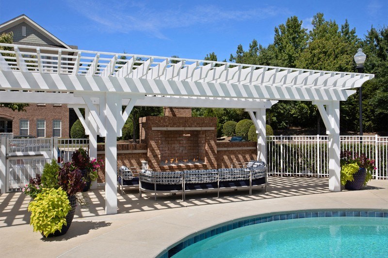 a pergola over a pool with lounge chairs