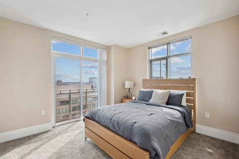 A bedroom with a large bed and a view of the city through the window.