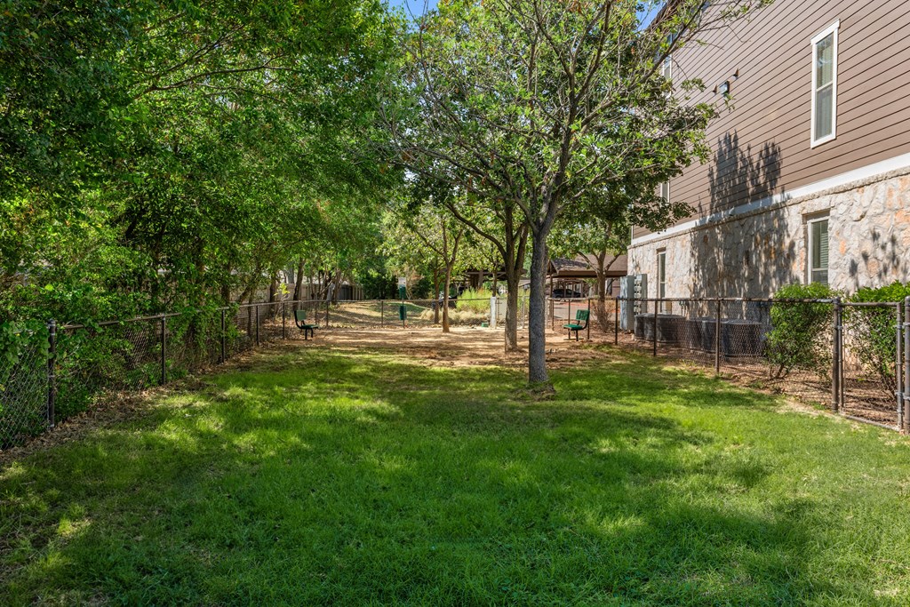 the back yard of a house with trees and a chain link fence