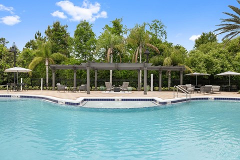 A pool with a deck and umbrellas.