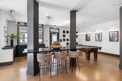 A room with a pool table and a bar area.