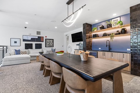 A modern dining room with a long wooden table and chairs.
