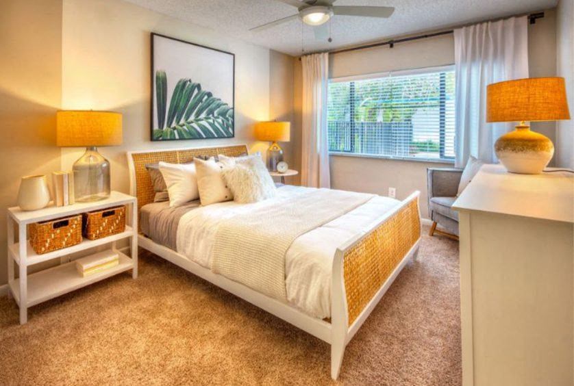 A bedroom with a large bed, two lamps, and a painting on the wall.