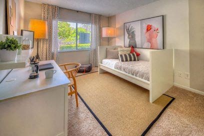 a bedroom with a bed and a desk and a window