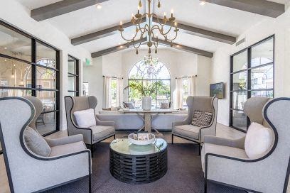 A living room with grey chairs and a chandelier.