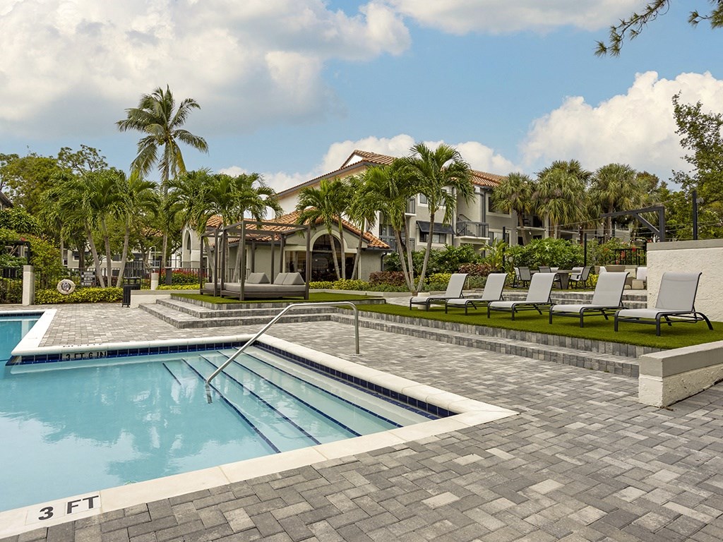 a swimming pool with lounge chairs next to a resort pool