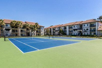 a tennis court with apartments in the background