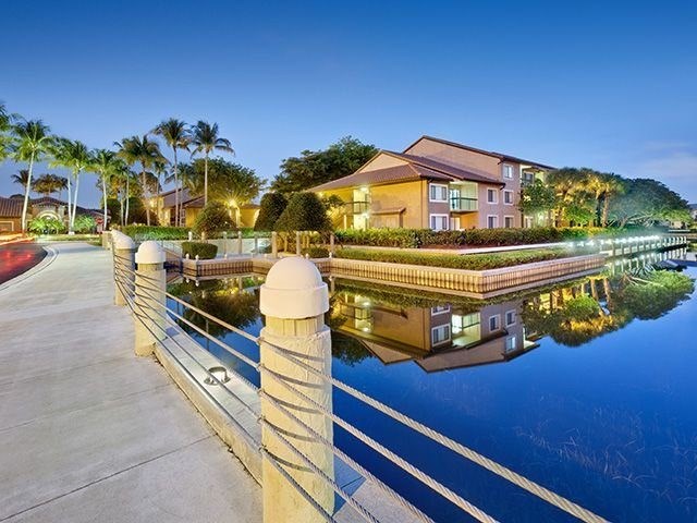A serene evening view of a residential area with a bridge and a building with lights on.