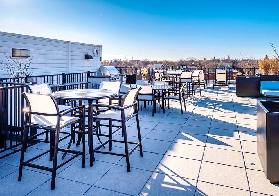 a rooftop patio with tables and chairs and a view of the city