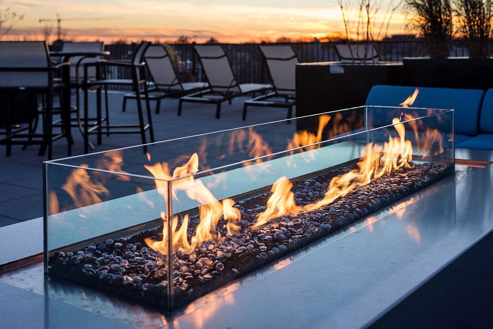 a glass fireplace with flames on a table with chairs