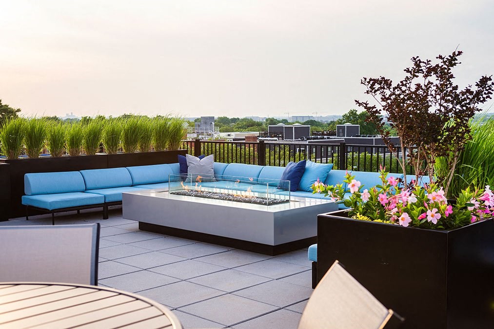 a rooftop patio with blue couches and a fire pit