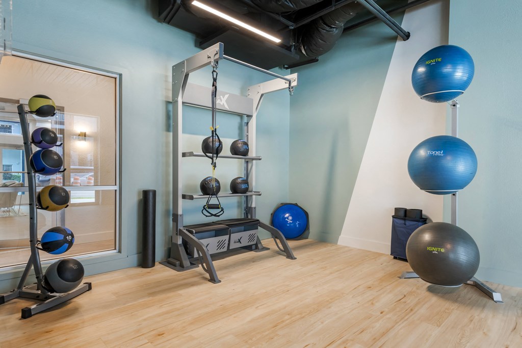 a fitness room with exercise equipment and balls on the floor