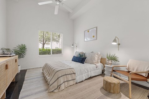 A bedroom with a bed, a chair, and a plant.
