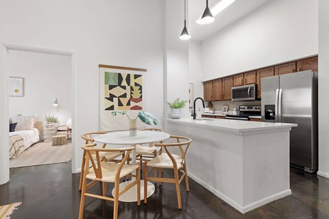 A kitchen with a white island and wooden chairs.