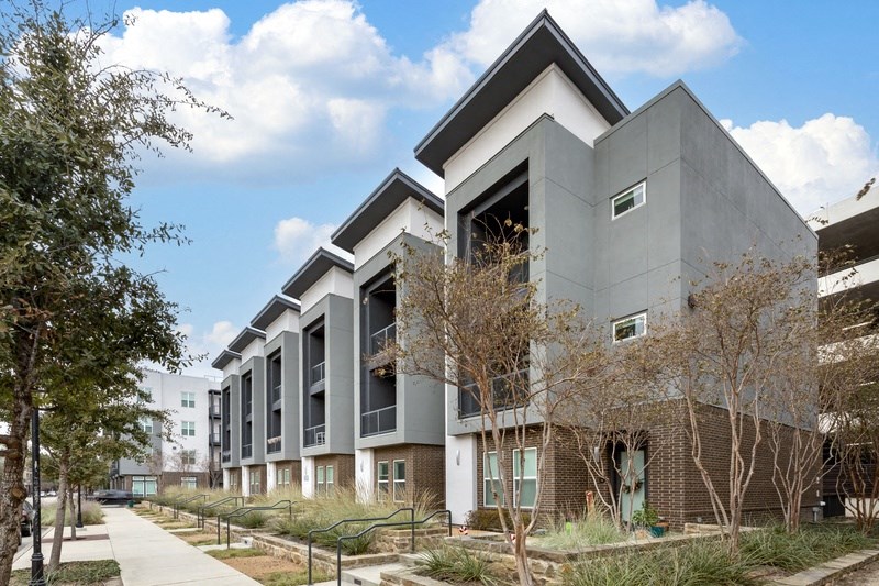 a row of apartment buildings with trees in front of them