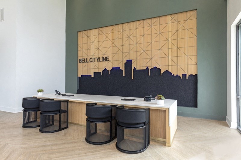 a long white table with four black stools in front of a large screen with a city