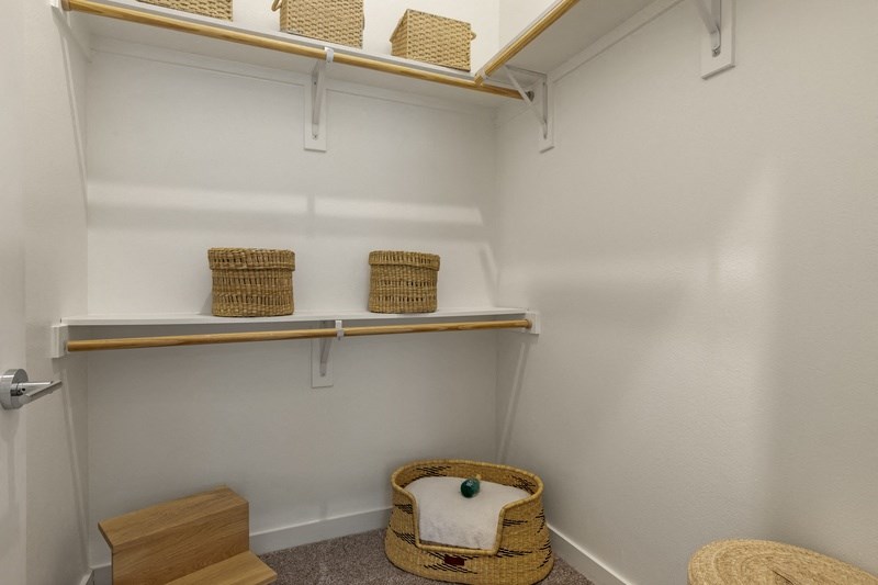 a walk in closet with wicker baskets and a wicker chair