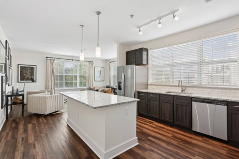 A modern kitchen with a white island and dark wood floors.