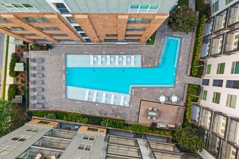 A swimming pool is surrounded by a brick wall and a glass ceiling.