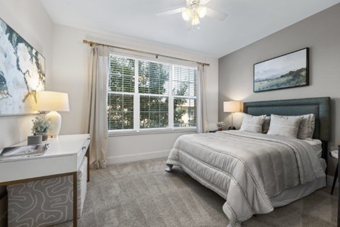 A bedroom with a large bed and a window with blinds.