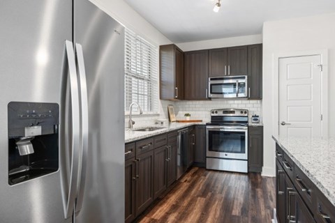 A modern kitchen with a stainless steel refrigerator and wooden floors.