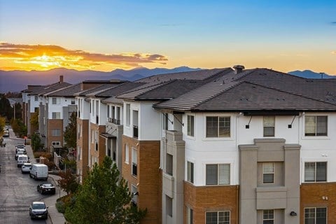 A sunset view of a street lined with apartment buildings.