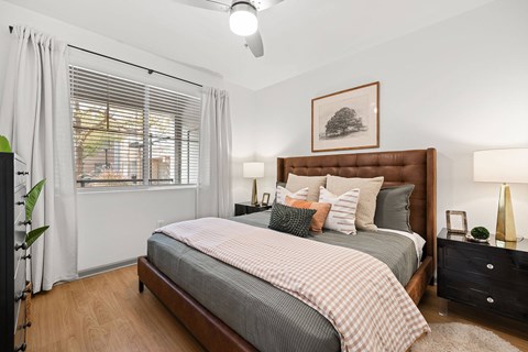 A bedroom with a large bed and a picture of a tree on the wall.