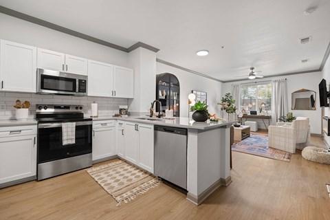 A modern kitchen with white cabinets and a wooden floor.