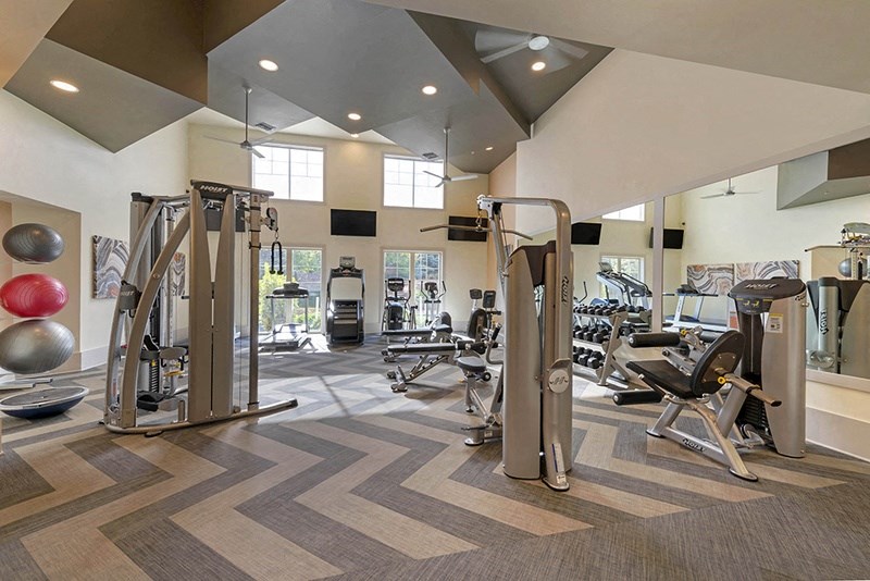 a gym with weights and cardio equipment in a building with vaulted ceilings