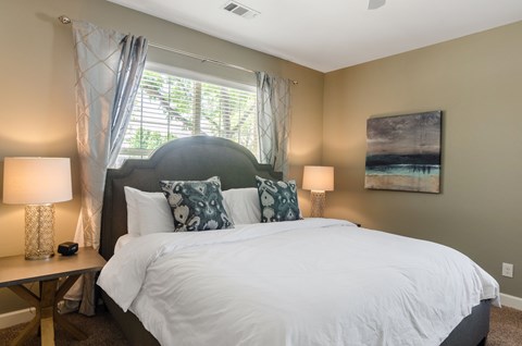 A bedroom with a large bed and a painting on the wall.